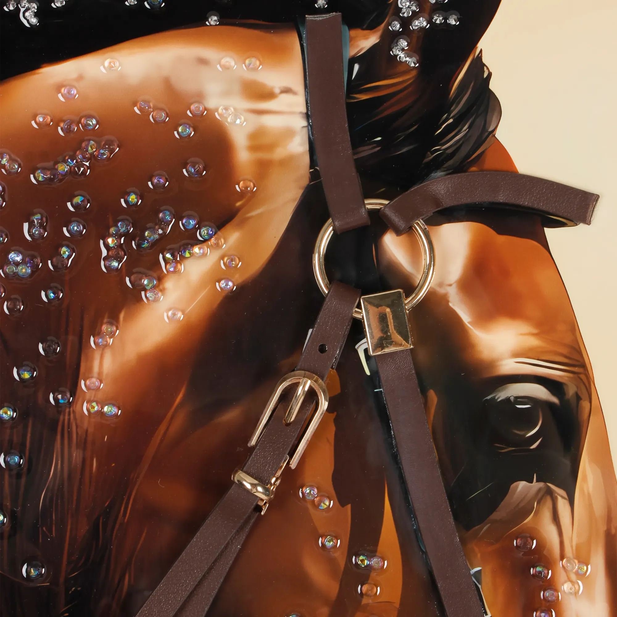 Close-up of a decorative brown leather knot tied on the horse's bridle strap, with iridescent crystal rhinestones scattered across the horse's glossy brown coat in the background.